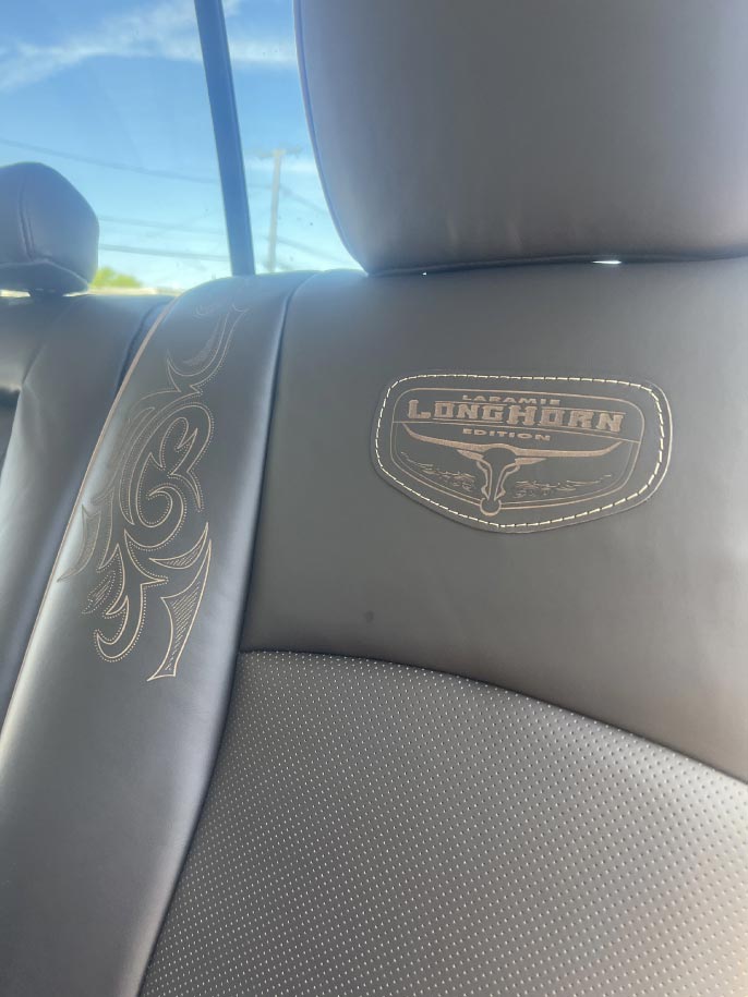 longhorn Custom black leather seat with laser-engraved scroll design and Laramie Longhorn Edition emblem by Central Valley Upholstery
